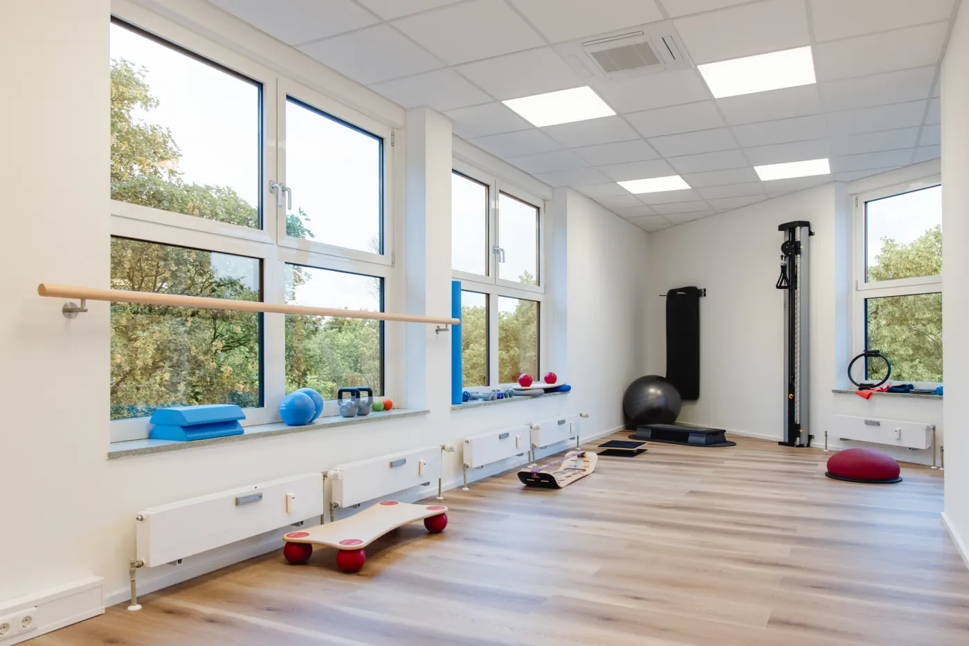 Heller Trainingsraum mit Ballettstange, Balancegeräten und Gymnastikball