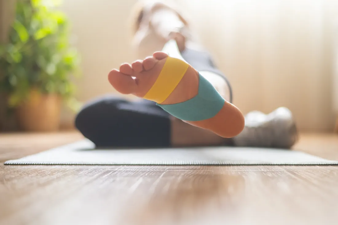 Fuß mit Kinesio-Tape bei einer Übung auf einer Gymnastikmatte zu Hause